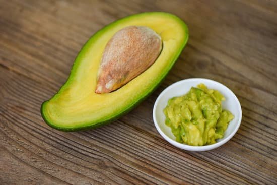 canva avocado sliced half and avocado dip mashed on wooden table MAD 3i PuwM