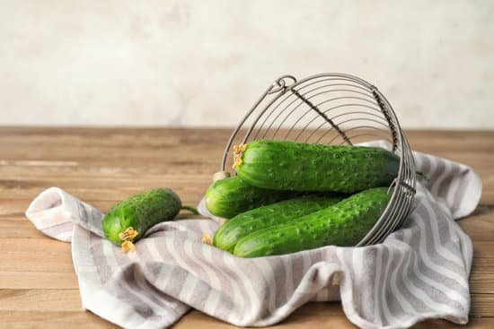 canva basket with green cucumbers on wooden table MAD6rHi1epA