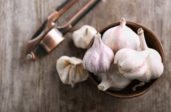 canva bowl with fresh garlic and crusher on wooden table MAD76oVBaJM