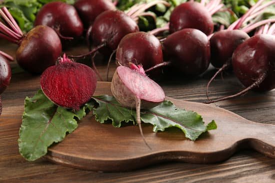 canva close up of ripe beets with leaves on wooden table MAD MbTFzcs