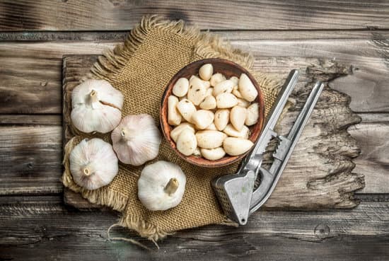 canva cloves in wooden bowl with garlic press on wooden board MAEPbgd4WIE
