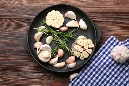 canva cloves of garlic and rosemary on wooden table MAD 76OhF5k