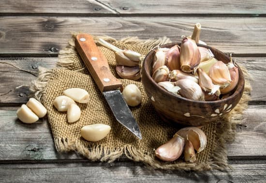 canva cloves of garlic in a bowl with a knife MAEPT5GhuwY