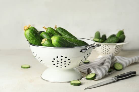 canva colander with green cucumbers on a table MAD6rHRd2pk