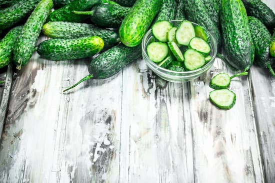 canva cucumbers and cucumber slices in a glass bowl.