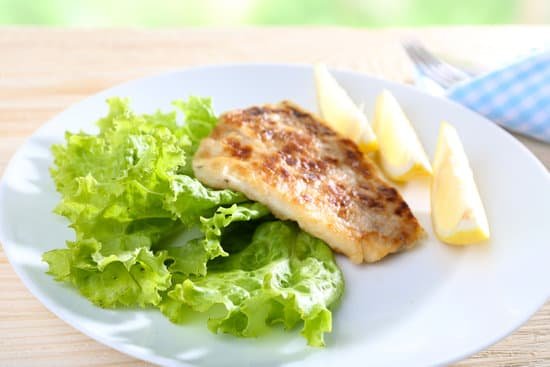 canva dish of fish fillet with lettuce and lemon on table MAD MTIoGHk