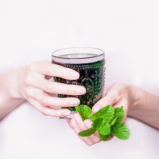 canva female hand holding glass of green chlorophyll drink with mint leaves on a light pink background MAEAc4CW9dc