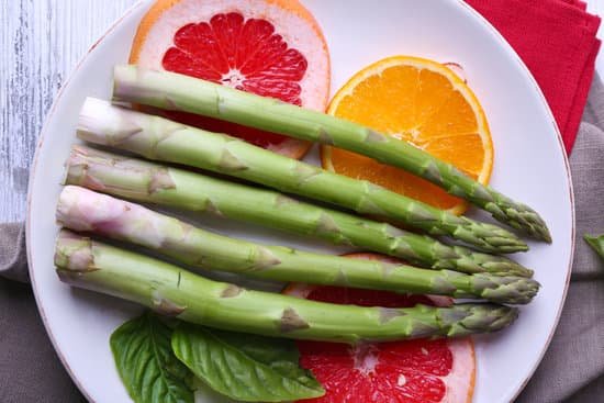 canva fresh asparagus and fruit slices on a plate MAD Ma4SJUE