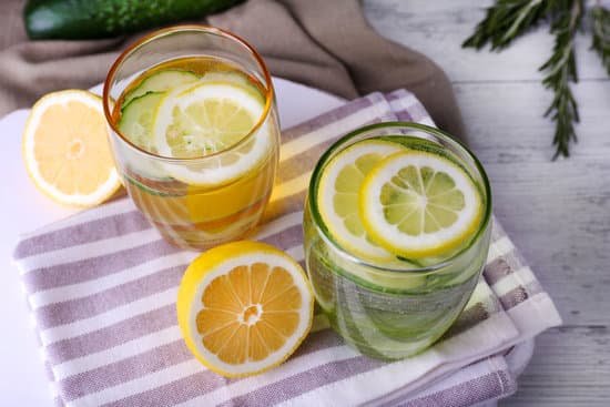 canva fresh water with lemon and cucumber in glassware on wooden table closeup MAD MEzEJm4