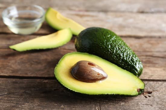 canva fresh whole and sliced avocados on wooden table close up MAD QrdnrXM