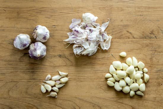 canva garlic bulbs cloves and peels on wooden table MAEEJn1p2Gc
