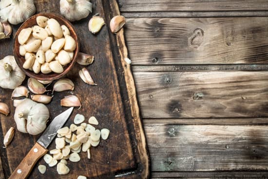 canva garlic cloves on a cutting board with a knife MAEPh2eMLzo