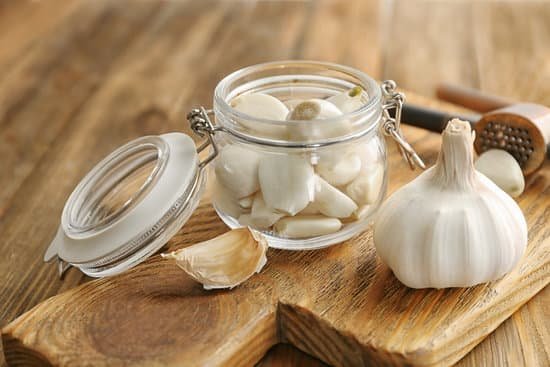 canva garlic press and jar with garlic on a wooden board MAD76kr3Pdk