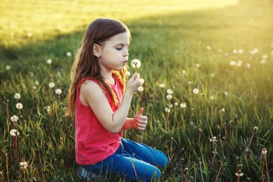 canva girl blowing dandelions in a meadow MAECKb3igno