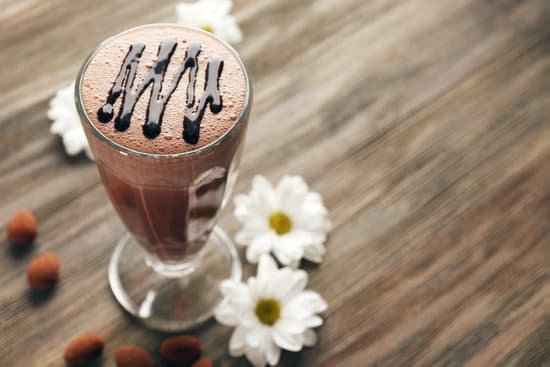 canva glass of chocolate milkshake and chamomile flowers on wooden background MAD QvbfWtw