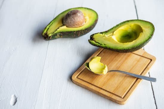 canva half cut avocado on a white wooden table