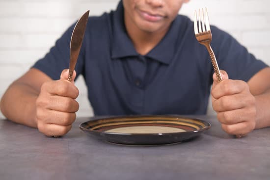 canva hand holding cutlery with empty plate on wooden table MAEYFd1fcaA