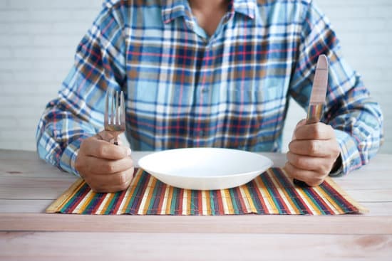 canva hand holding cutlery with empty plate on wooden table MAEjs5Qj7OM