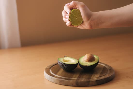 canva hand squeeze lime juice on fresh sliced avocado.