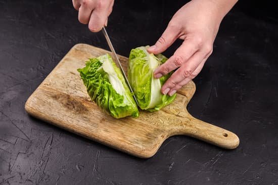 canva hands cutting iceberg lettuce on wooden chopping board MAEAGDeyJCY