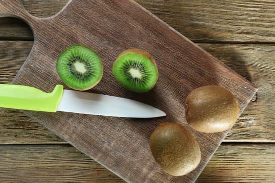 canva kiwi with knife on cutting board on wooden background MAD MfZ90S8