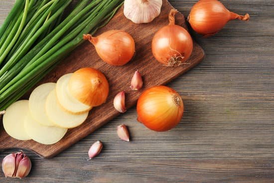 canva onions with garlic on board on wooden background MAD M41P9D8