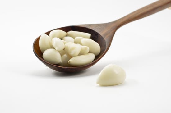 canva peeled garlic cloves on wooden spoon MAEQTSA7UGw