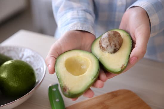 canva person holding fresh half sliced avocado MAD Qoi7WIE