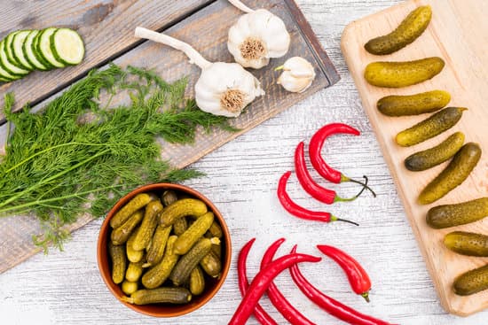canva pickled cucumber dill chili peppers and garlic on a table MAD gZv5sr8