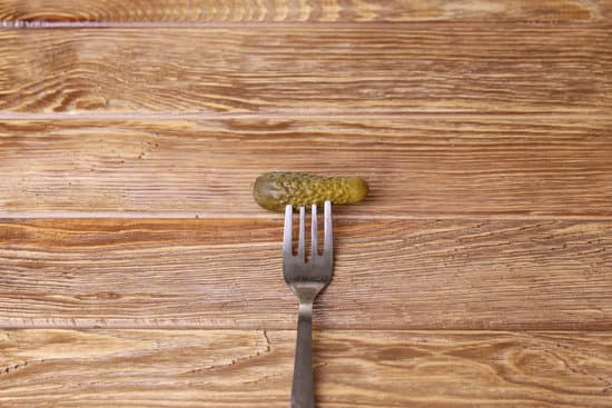 canva pickled cucumbers in a fork on wooden table MAEPqanNjWQ