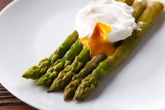 canva roasted asparagus with poached egg on plate on table MAD MX8HdPw