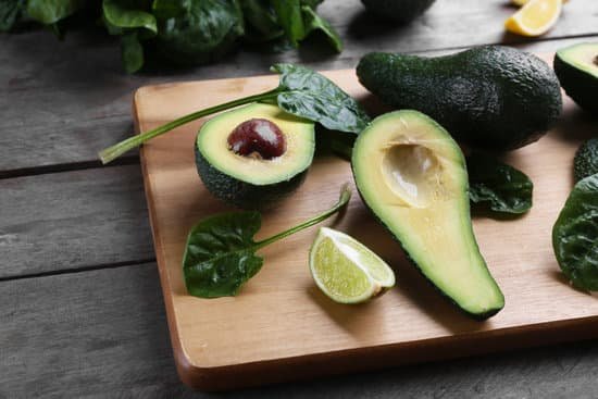 canva sliced avocado with lime and spinach on wooden board MAD QuzQL5k