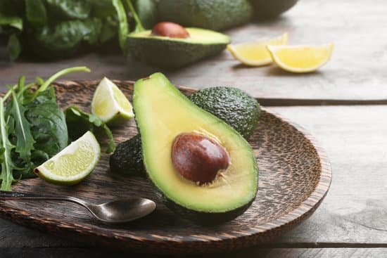 canva sliced avocado with lime and spinach on wooden plate MAD QuunTU4