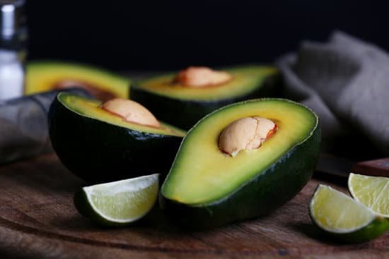 canva sliced avocado with lime on wooden cutting board on black background MAD MDm8ZRg