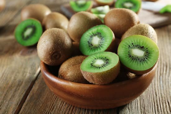 canva sliced juicy kiwi fruit in bowl on wooden table MAD MWiRKMA