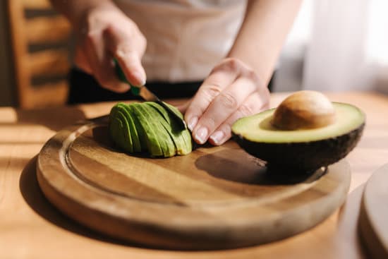 canva slicing avocado on wooden board MAERFeuzjdo