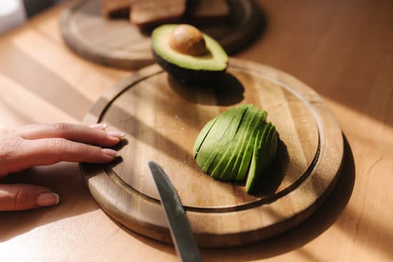 canva slicing avocado on wooden board at home. MAERFVV 0M