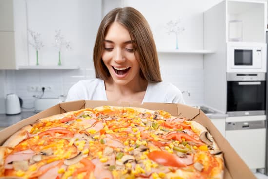 canva smiling woman holding hot pizza in box at home. MAEeeBYBMes