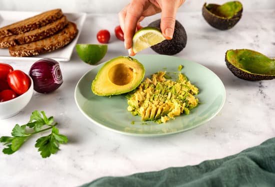 canva squeezing a slice of lime on mashed avocado in a plate