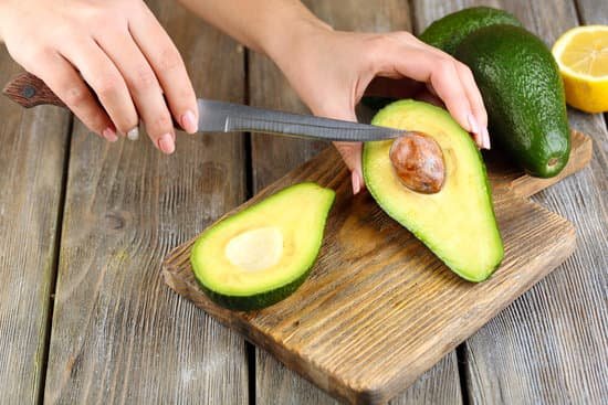 canva woman cuts avocado on wooden chopping board on table MAD MJpA3Pw