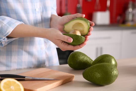 canva woman holding fresh avocado in the kitchen MAD QkzGD5A