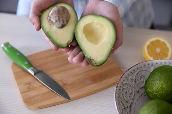 canva woman holding fresh avocado in the kitchen MAD QtW9yb4