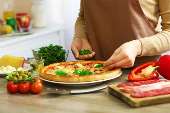 canva woman putting basil on pizza MAD QrTroLA