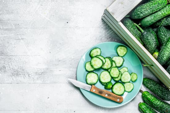 canva wooden box with cucumbers and slices on plate with knife MAEPbki43aY