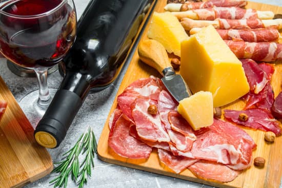 canva cheese and meat platter bottle and glass of red wine MAEPIwLF yw