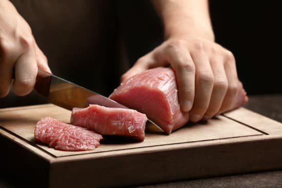 canva chef cutting fresh raw meat on wooden board MAD9T 6JQs