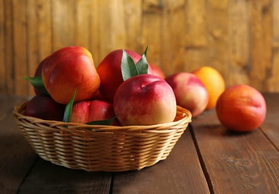 canva fresh peaches in wicker basket on wooden background MAD MtomEAc