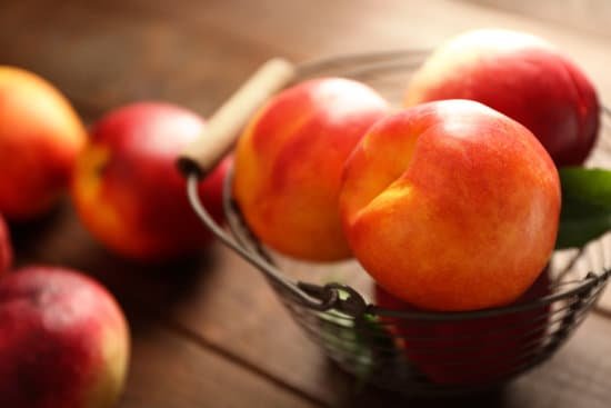 canva fresh peaches in wicker basket on wooden background MAD MvgT4DM