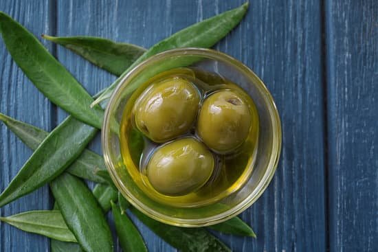 canva glass bowl with olives and oil on wooden background