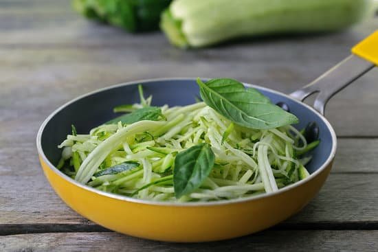 canva grated zucchini and basil in pan on wooden table MAD MbaJ03c